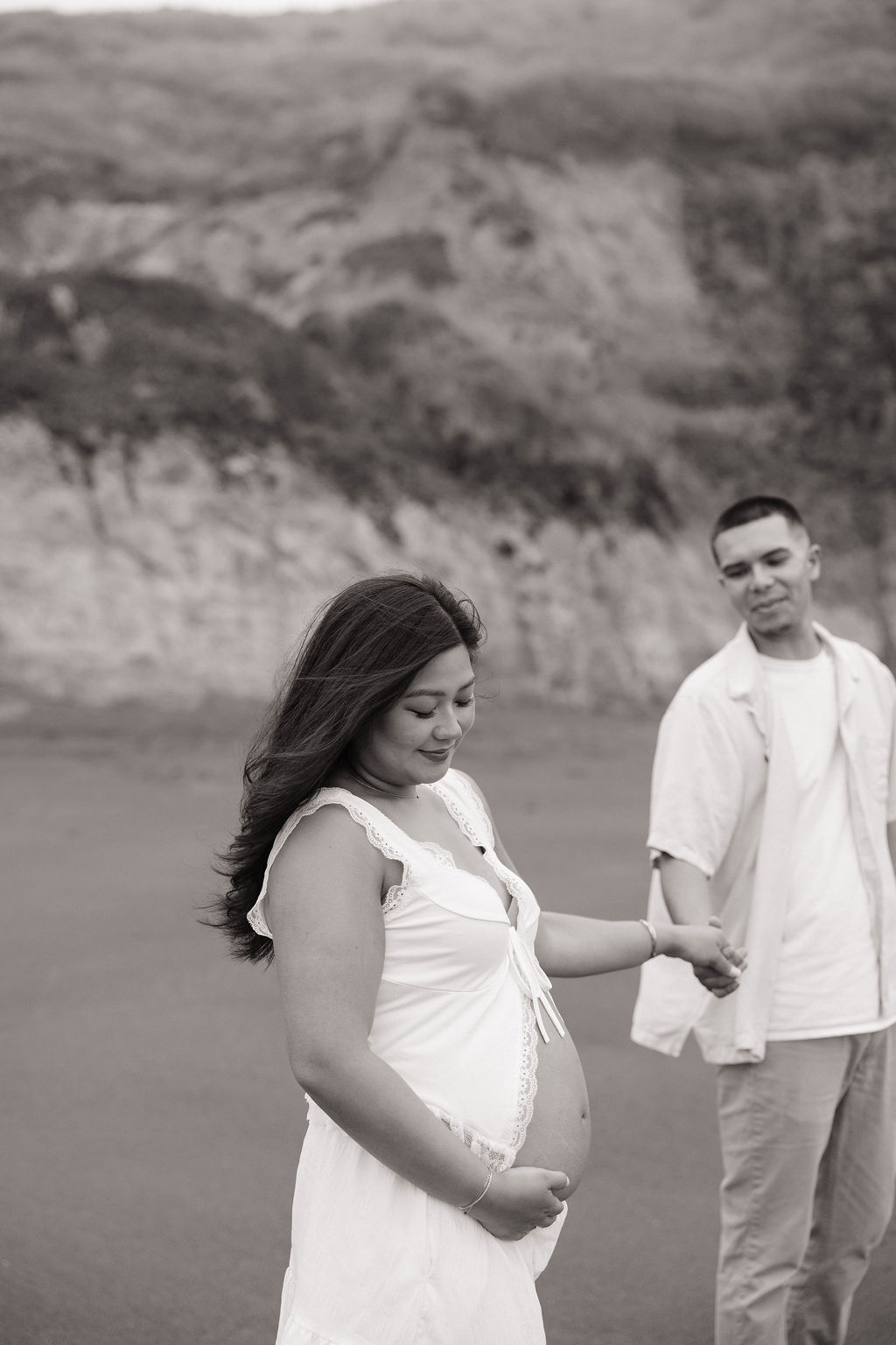 A woman holding her belly during beach maternity photos