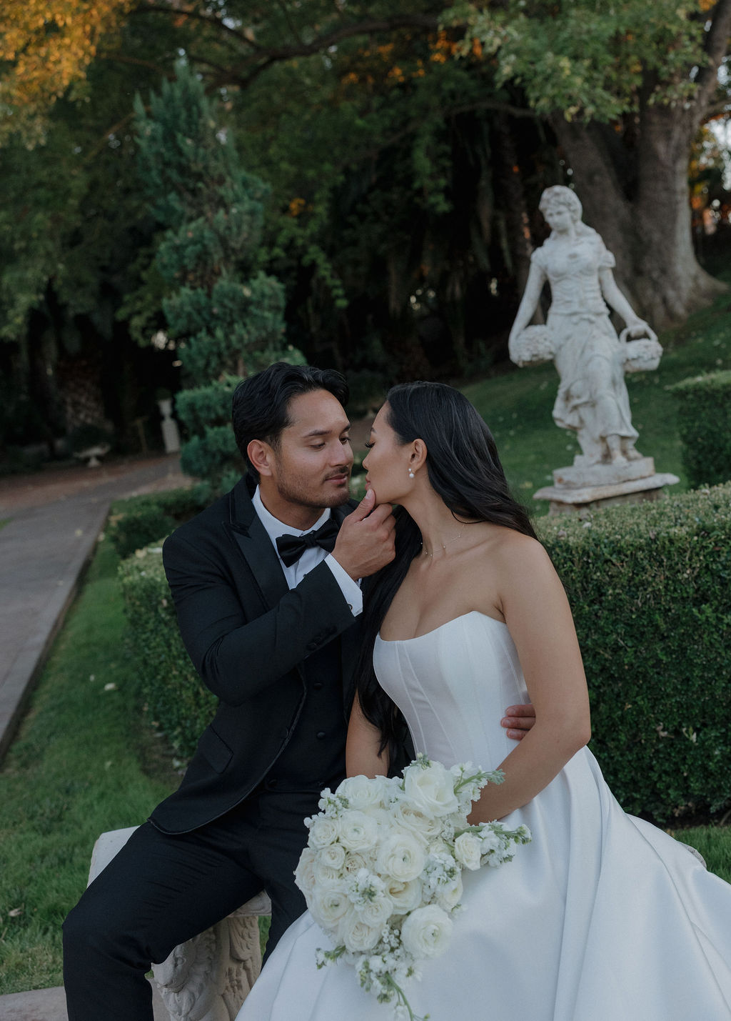 A couple leaning in for a kiss in the gardens at grand island mansion
