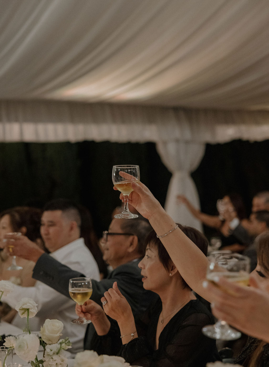 Wedding guests raising their glasses for toasts at a wedding reception