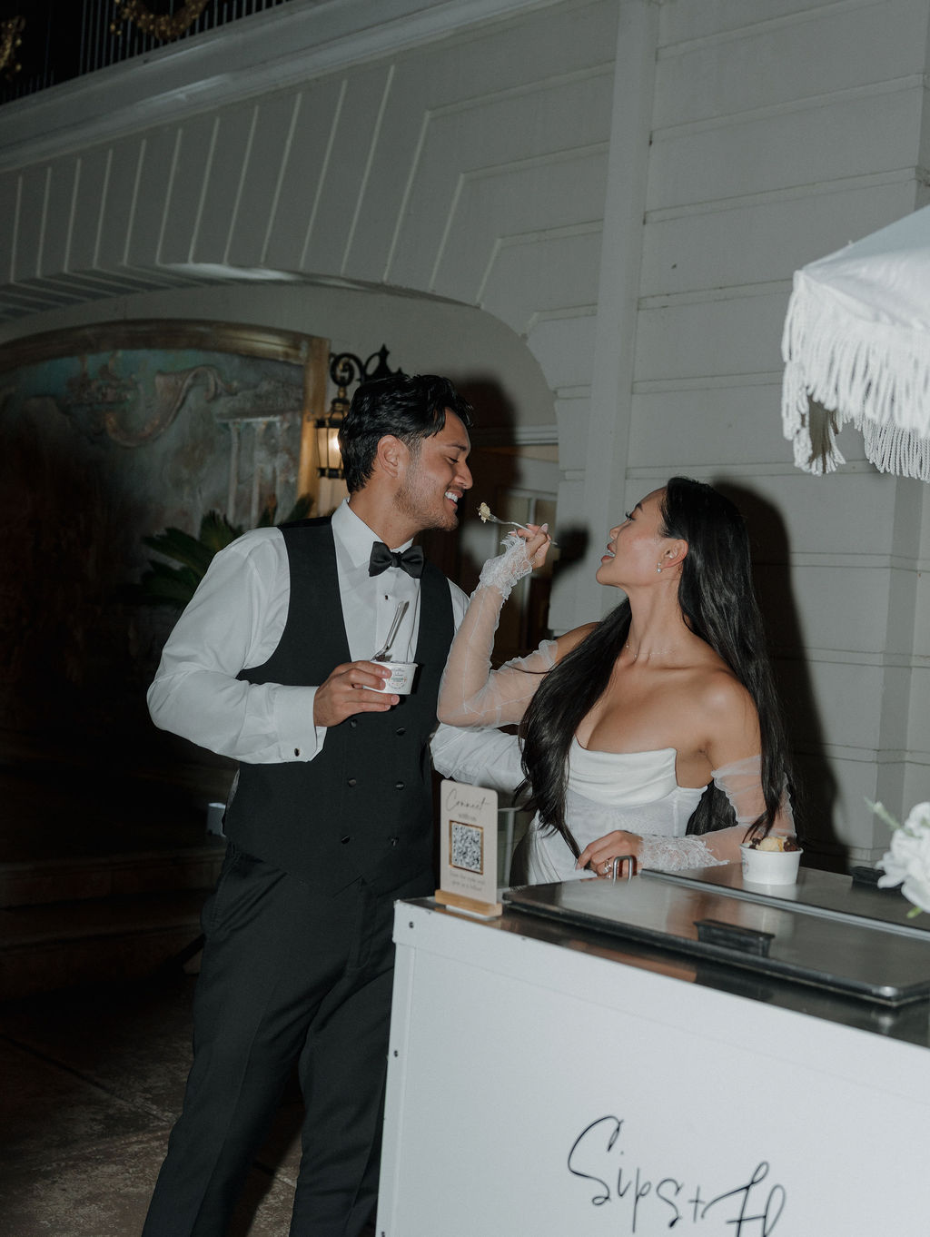 A bride and groom feeding each other ice cream at their wedding reception