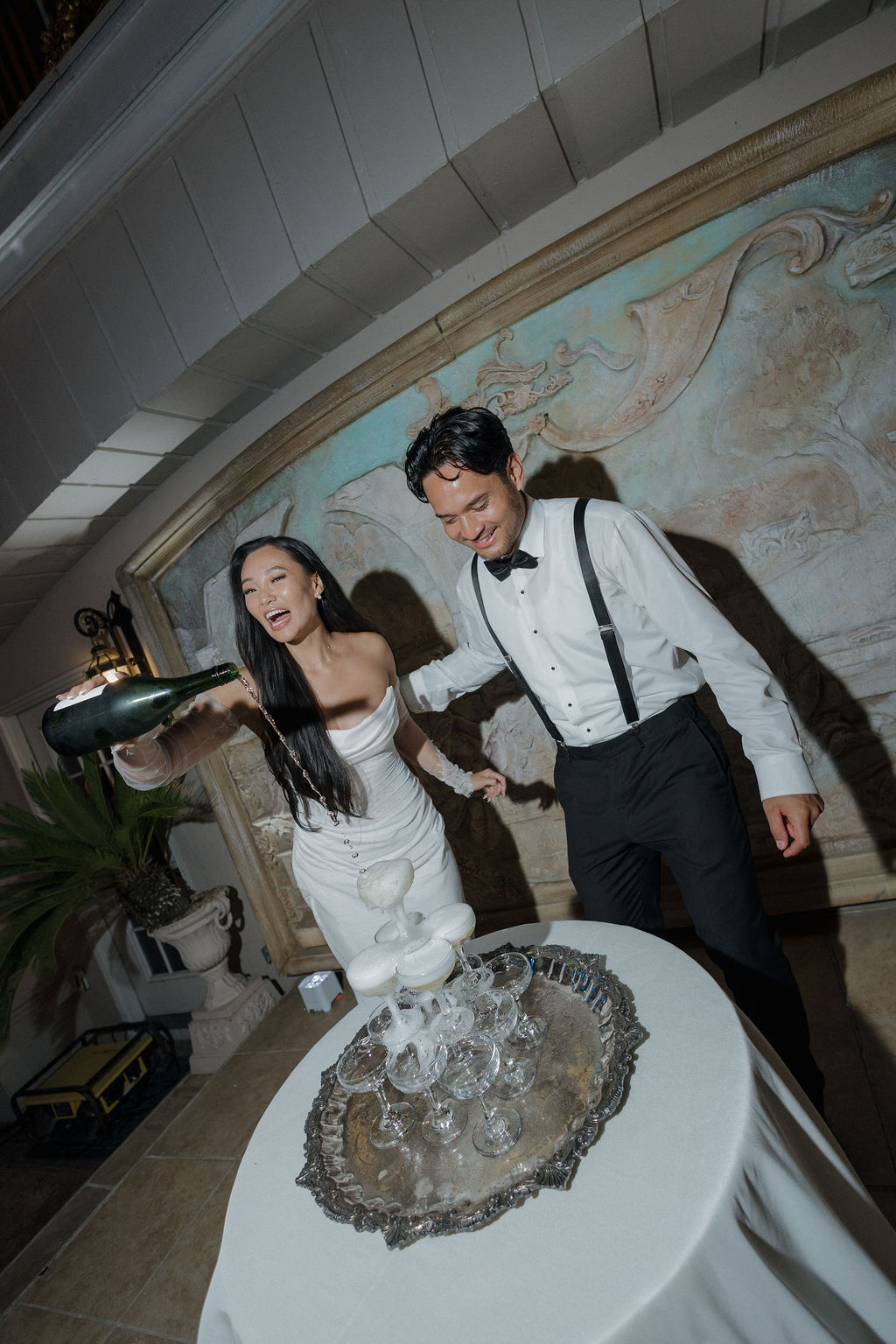 A bride and groom pouring a champagne tower at their wedding reception