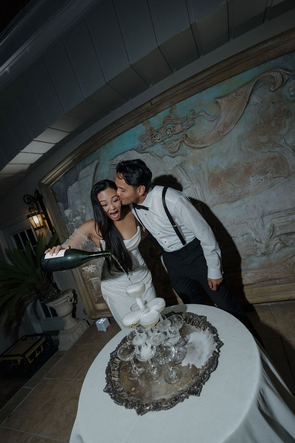 A bride and groom pouring a champagne tower at their wedding reception