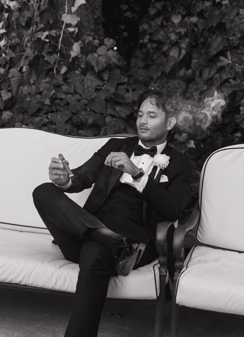 A groom smoking a cigar before a grand island mansion wedding