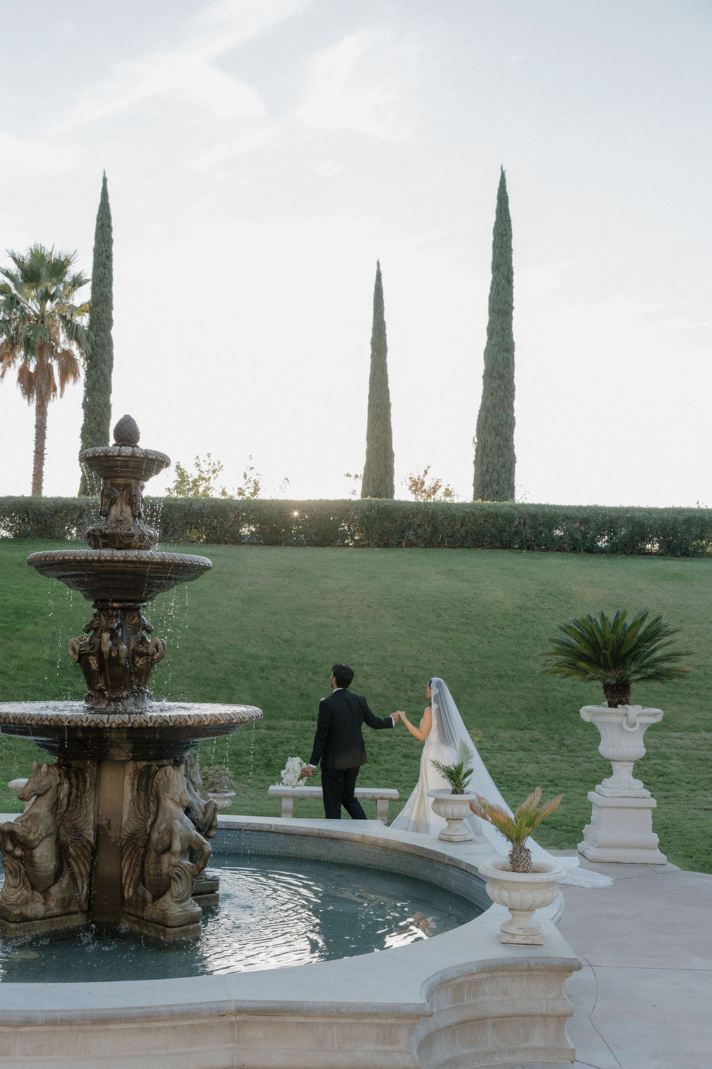 A couple walking through the gardens after their grand island mansion wedding