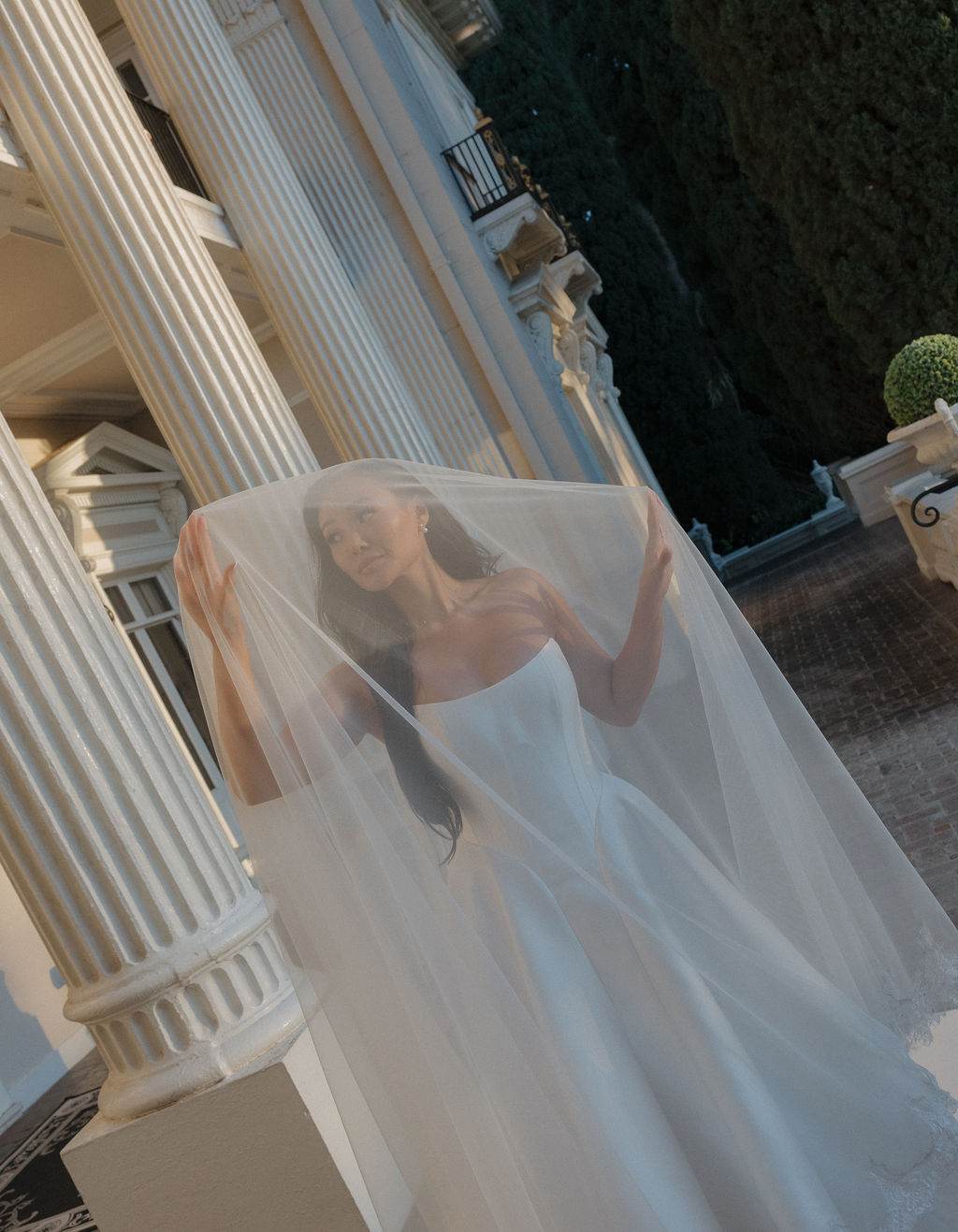 A bride posing for bridal portraits on the balcony at grand island mansion underneath her veil