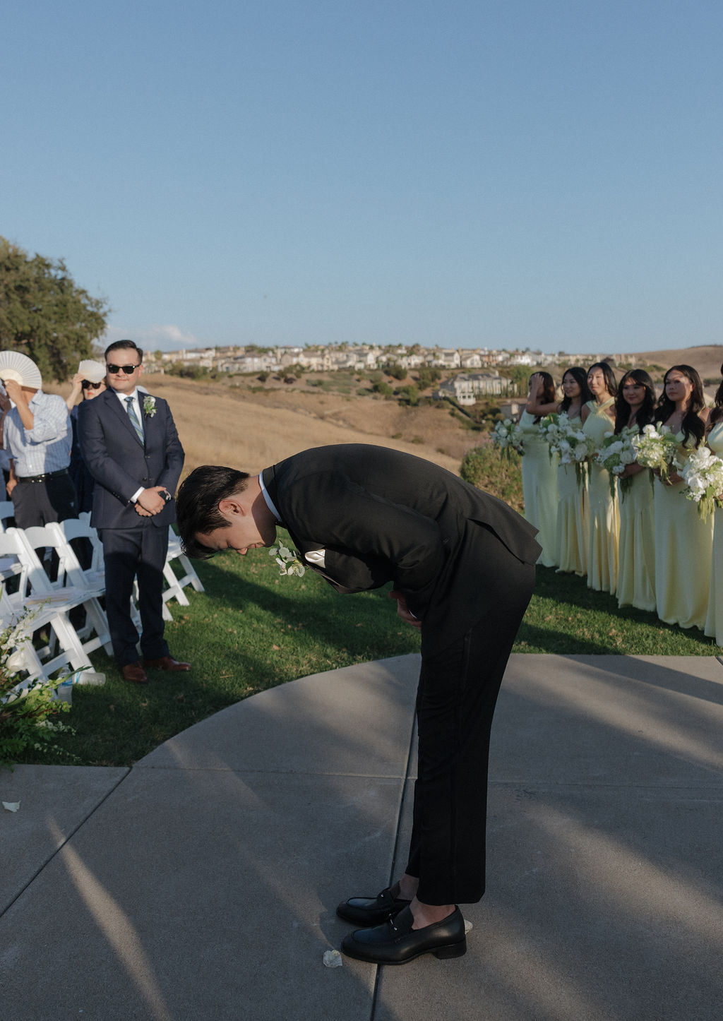 A groom bowing to the bride's parents walking her down the aisle