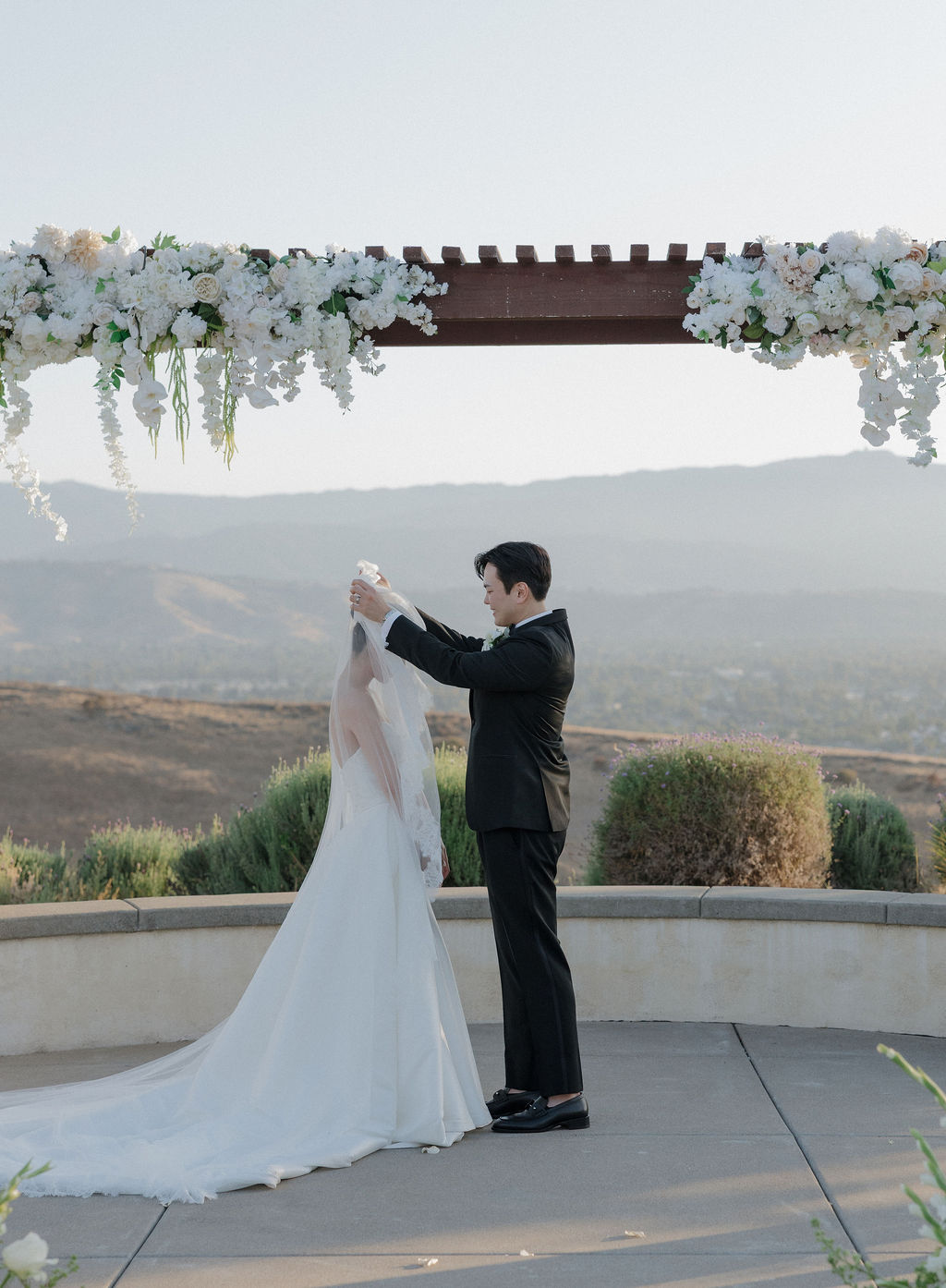 A groom flipping the bride's blusher veil over her head for luxury wedding ideas