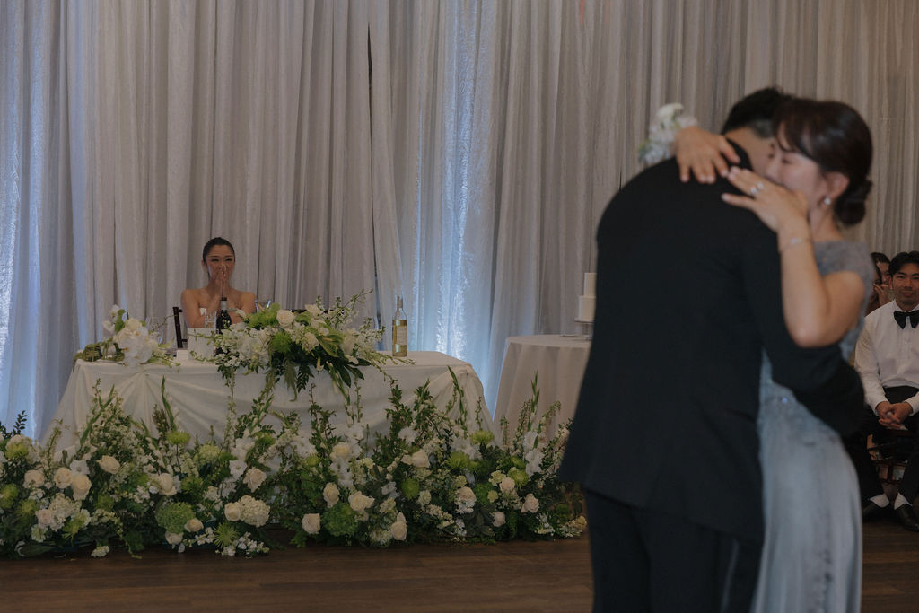 A bride crying while watching her groom dance with his mother