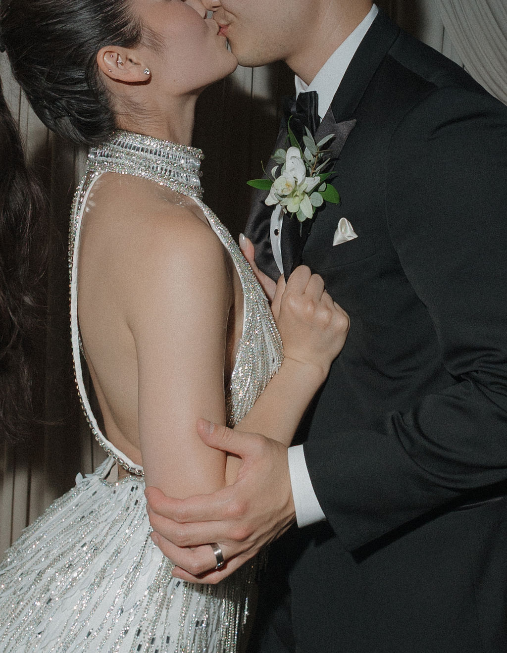 An up-close photo of a bride and groom kissing in their wedding reception outfits