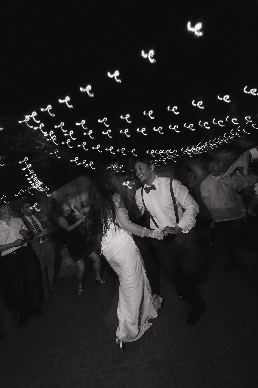 a wedding couple dancing under string lights