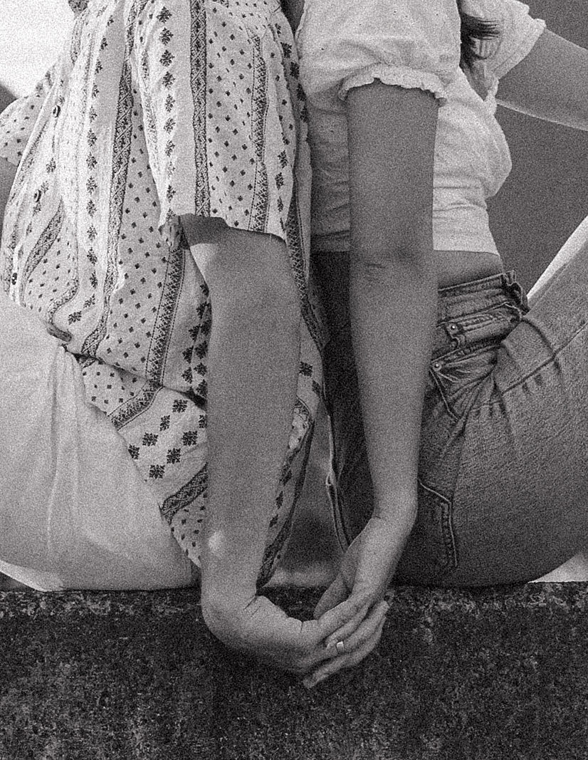 A couple sitting on Hanalei Bay Pier holding hands