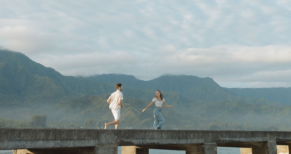 A couple running on Hanalei Bay pier in a photo taken by a Kauai photographer