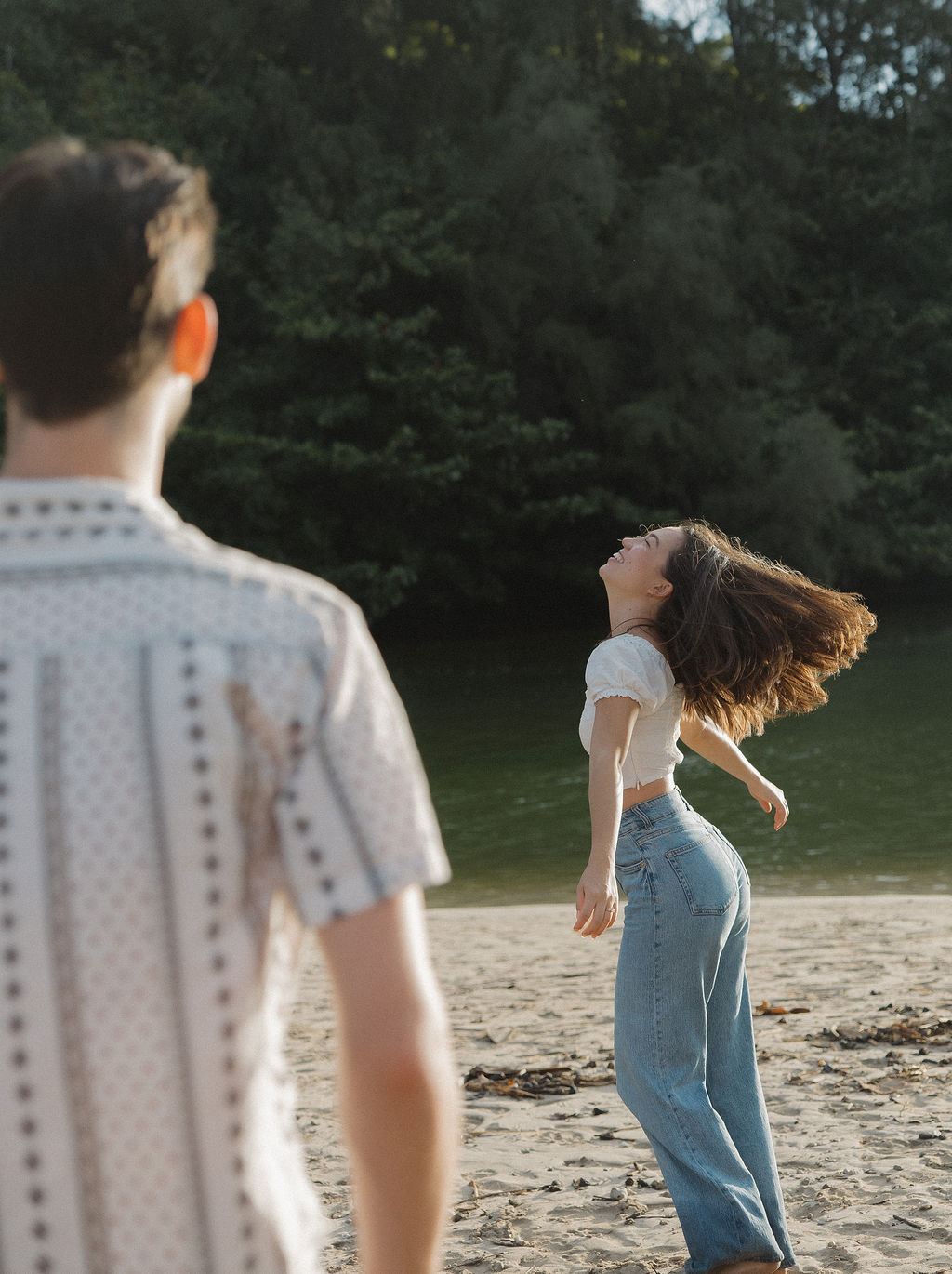 A man watching his fiancee on the beach during engagement photos