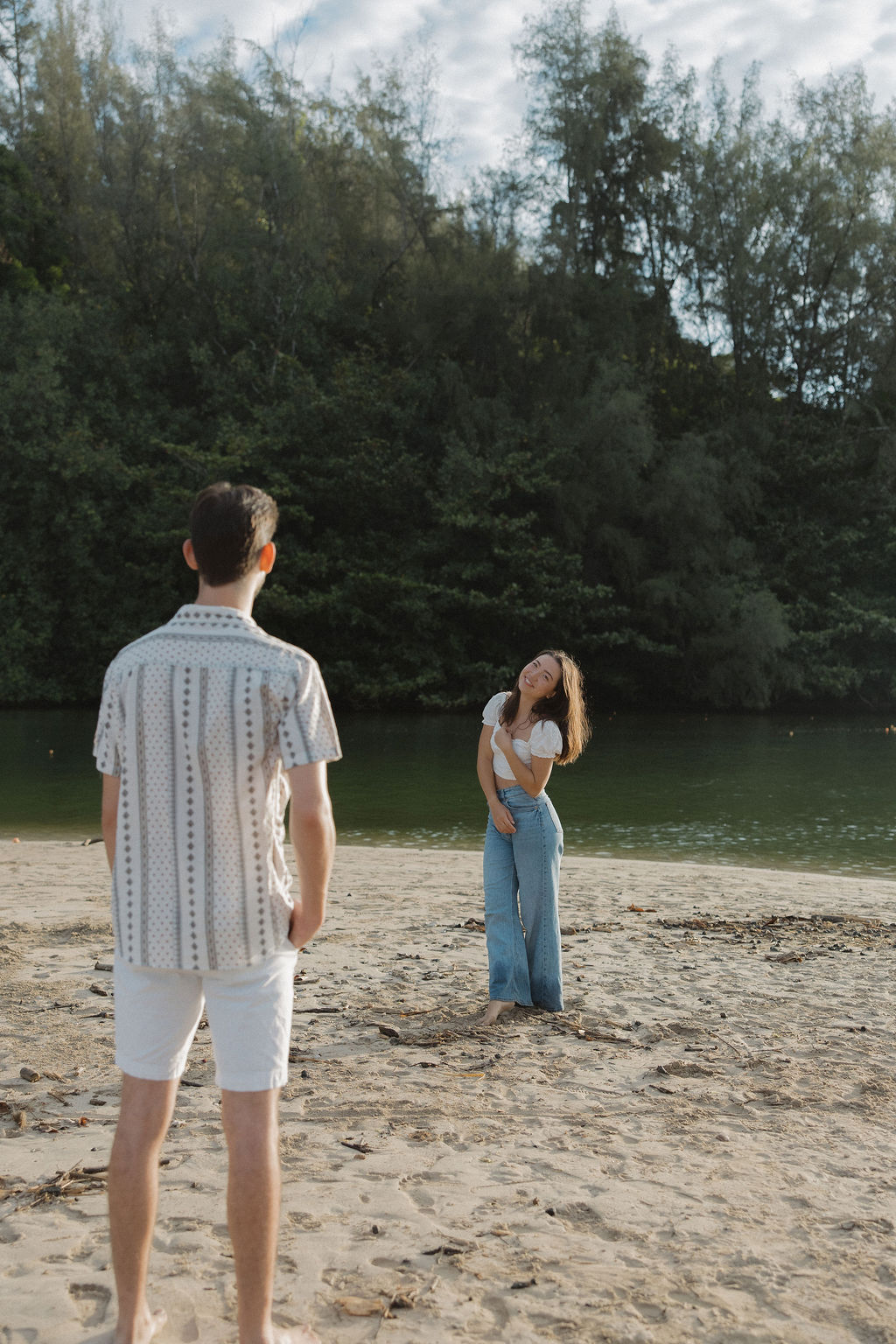 A man watching his fiancee on the beach during engagement photos