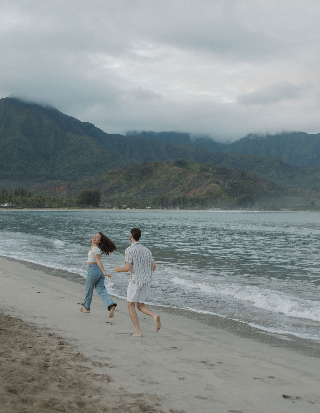 A couple running on the beach during their beach engagement photos