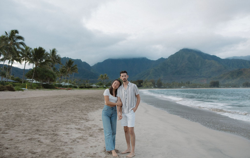 A couple posing for engagement photos on the beach at Hanalei Bay with a Kauai photographer