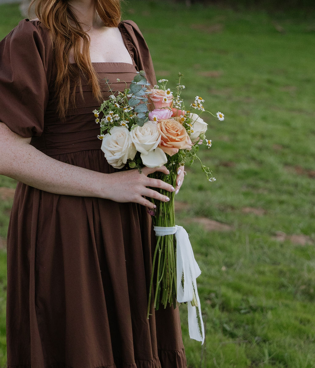 A girl holding a bouquet in a brown dress