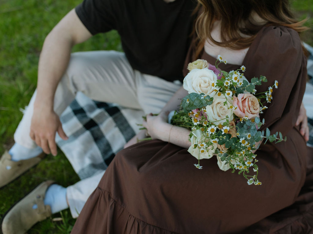 Engagement photoshoot ideas from a couple on a picnic blanket with flowers