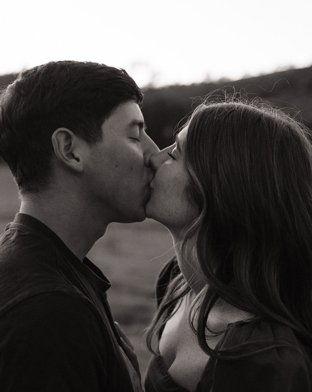 A black and white photo of a couple kissing during their engagement photos