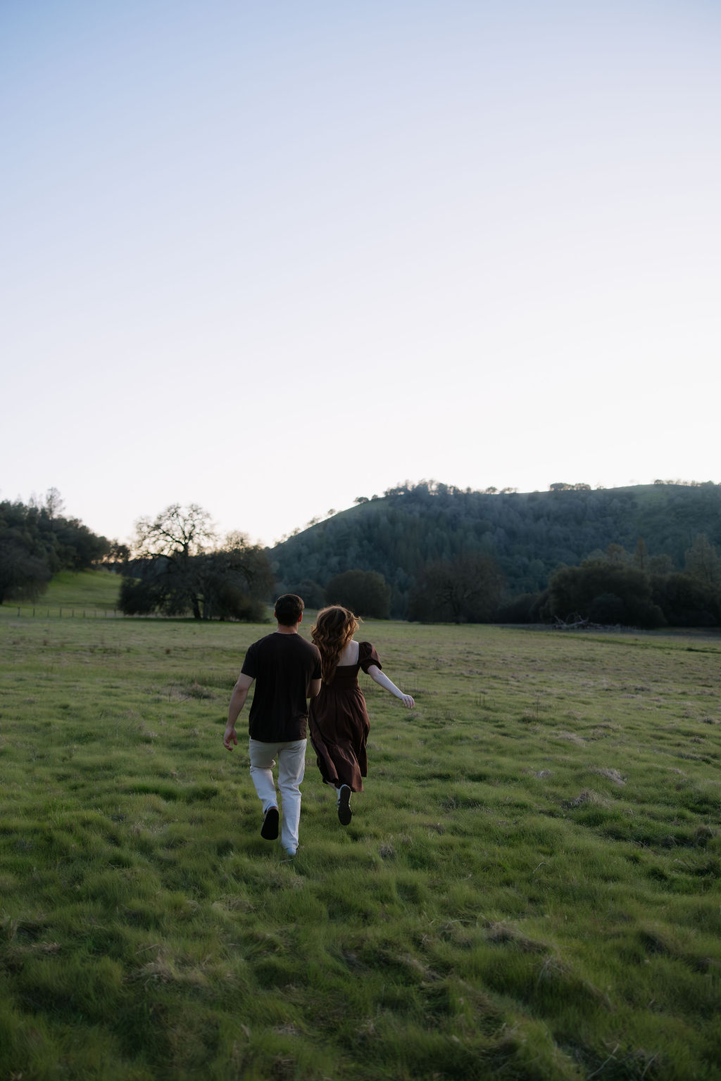 A couple running through a field during their El Dorado engagement photos