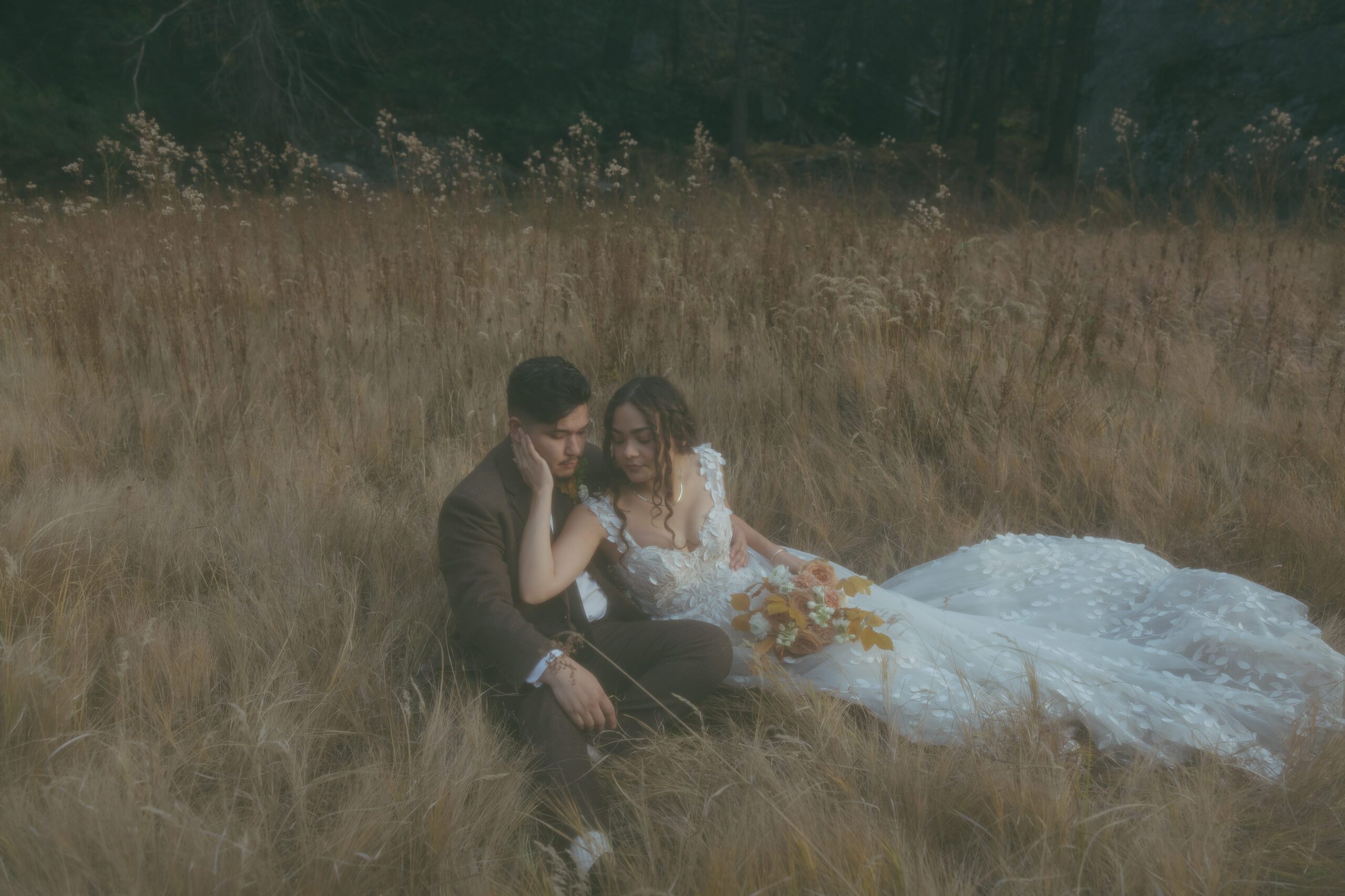 A bride and groom posing for wedding photos in a field in Yosemite, their Northern California wedding location 