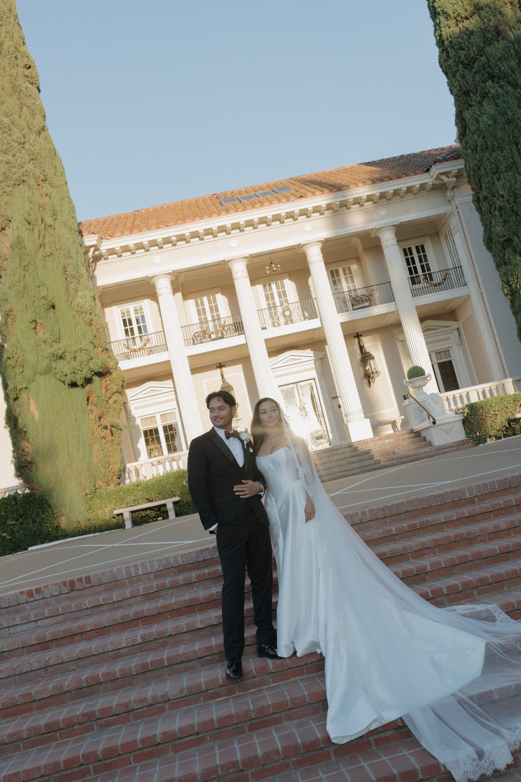 A bride and groom posing in front of their Northern California wedding location, Grand Island Mansion