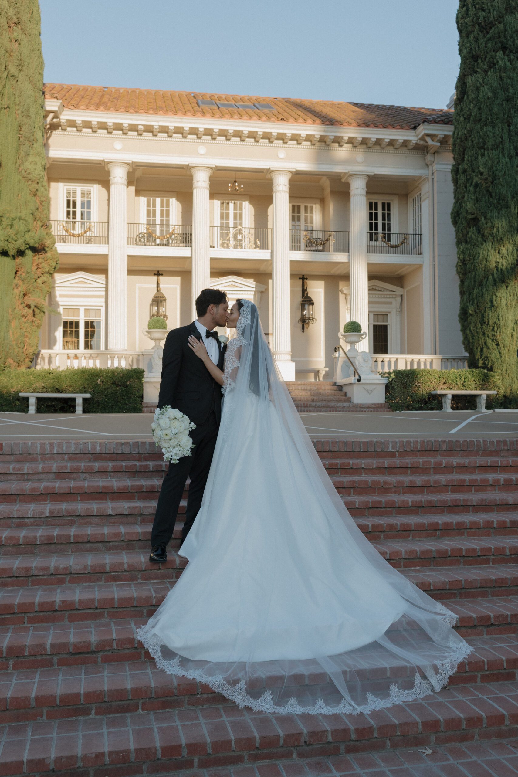 A bride and groom posing in front of their Northern California wedding location, Grand Island Mansion