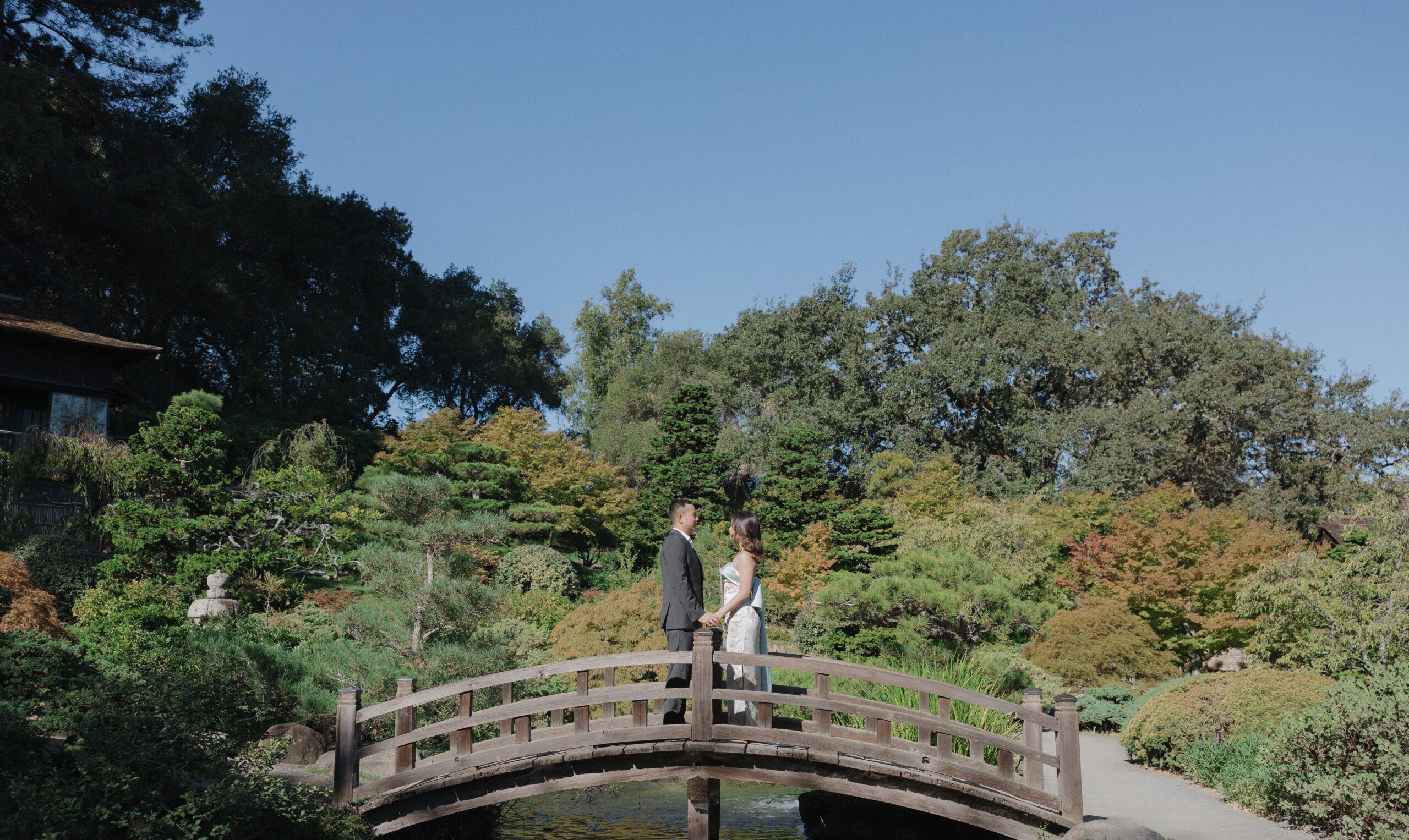 A bride and groom posing for wedding photos on a bridge in Hakone estate