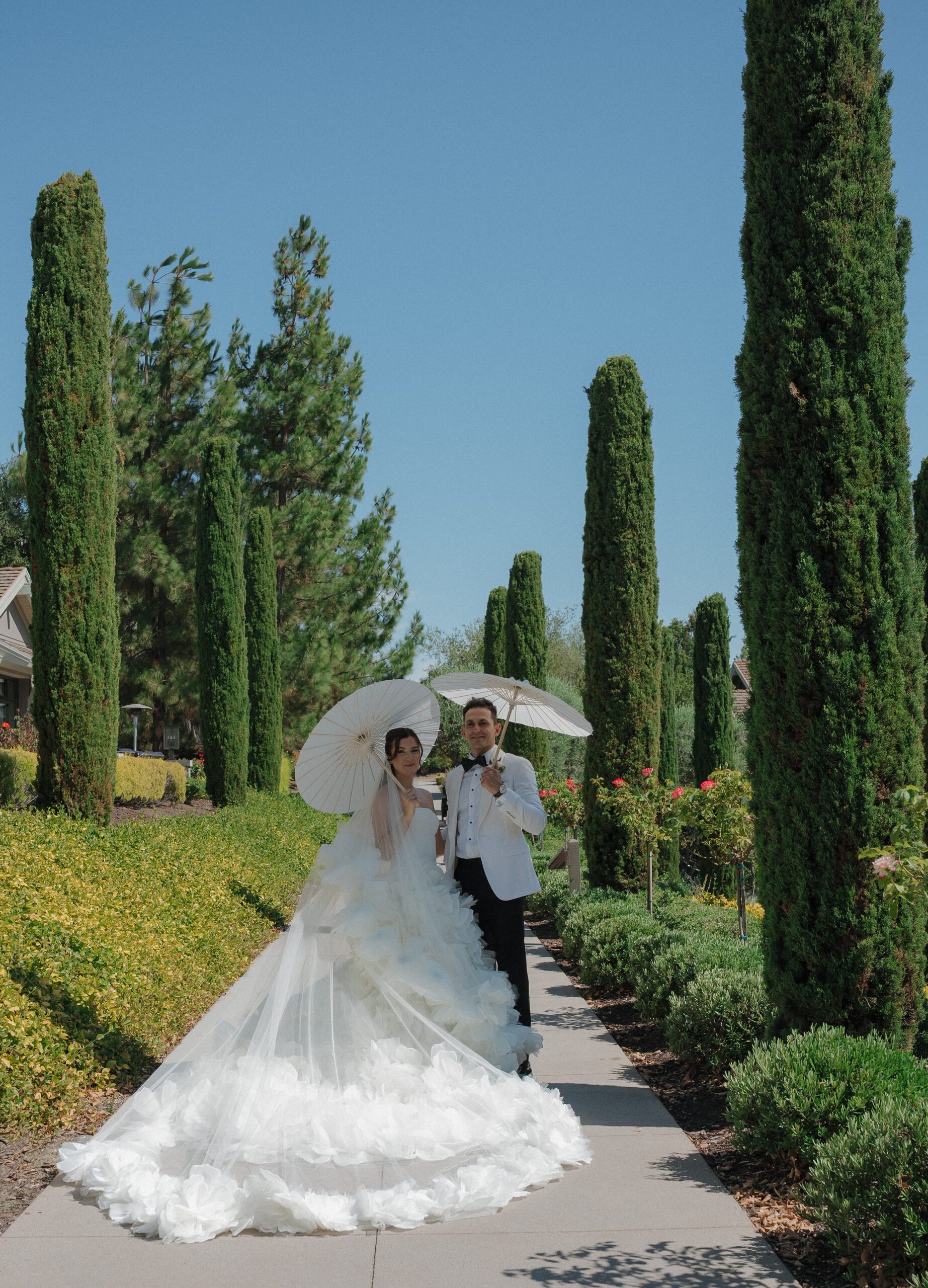 A wedding couple posing for photos at Rosewood Sand Hill with parasols