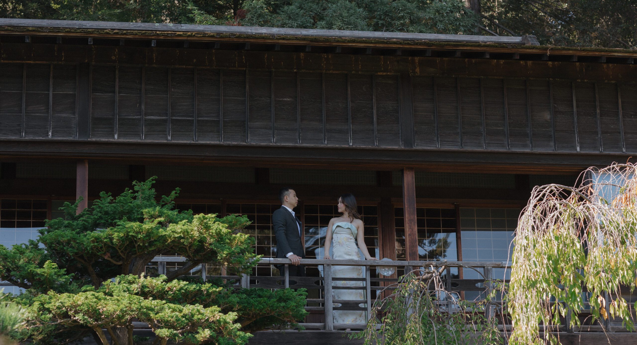 A bride and groom posing for wedding photos on a balcony at Hakone Estate and gardens