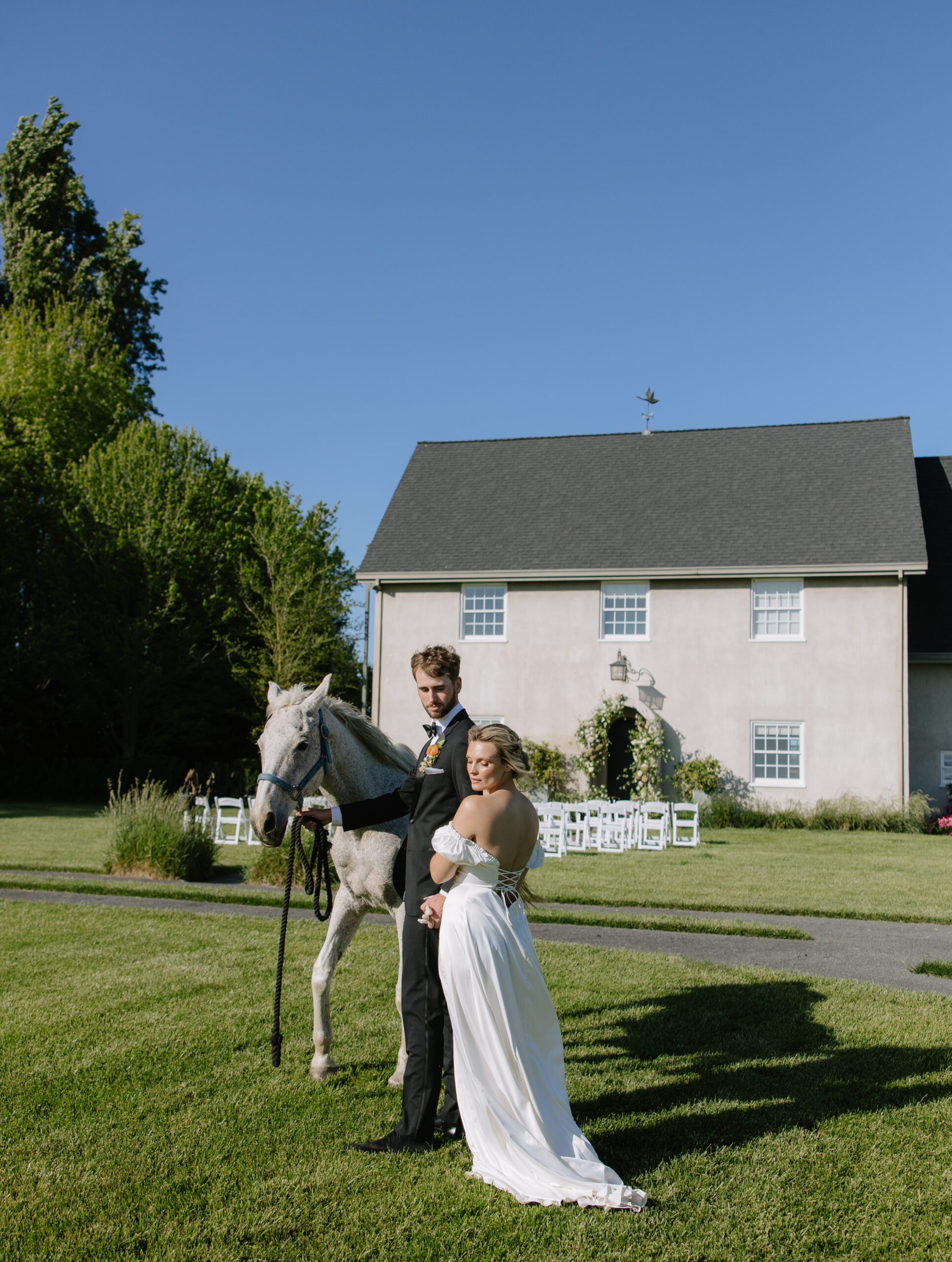 A bride and groom posing for photos with a horse at CAvaignac, their NorCal wedding venue