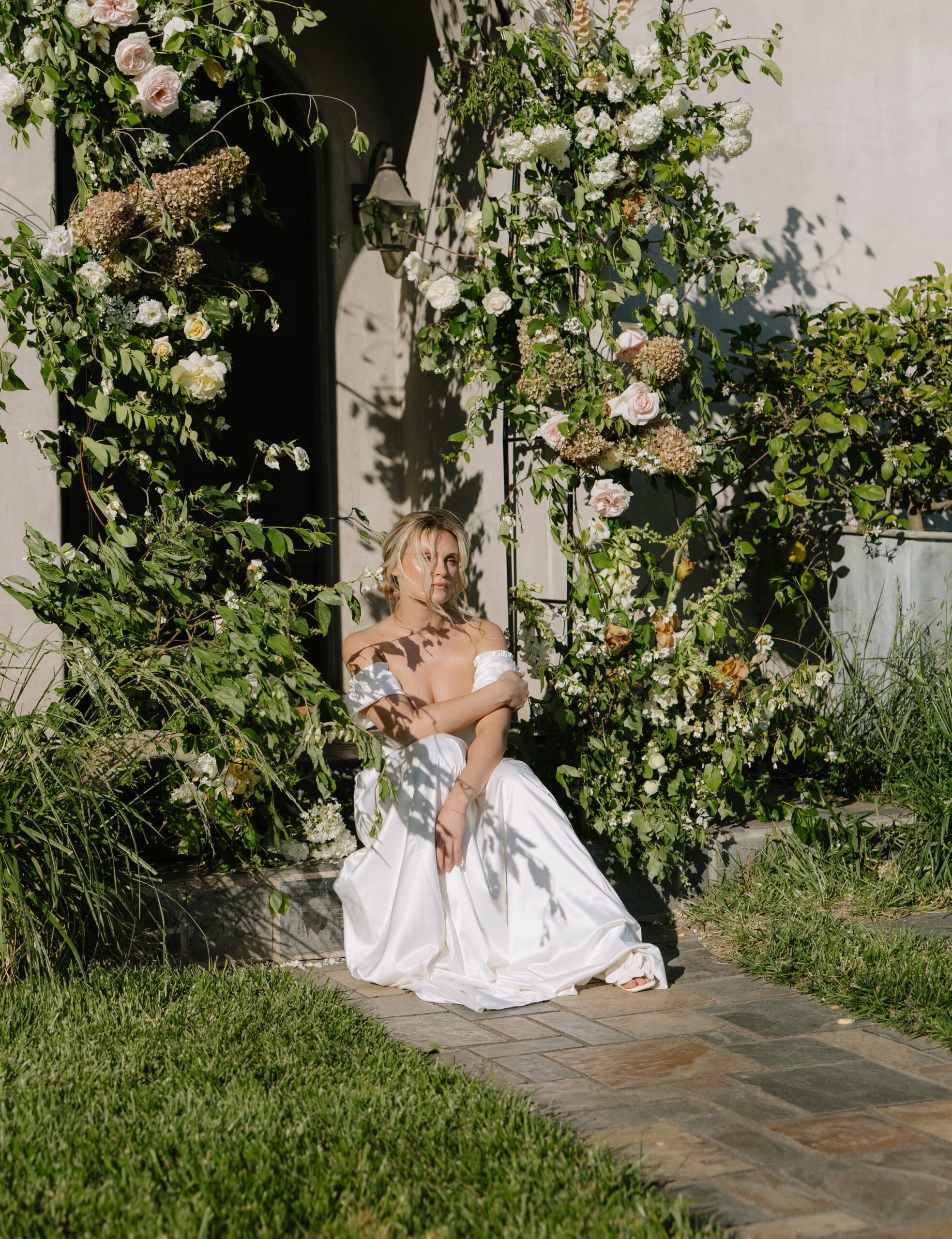 A bride sitting in her ceremony arch