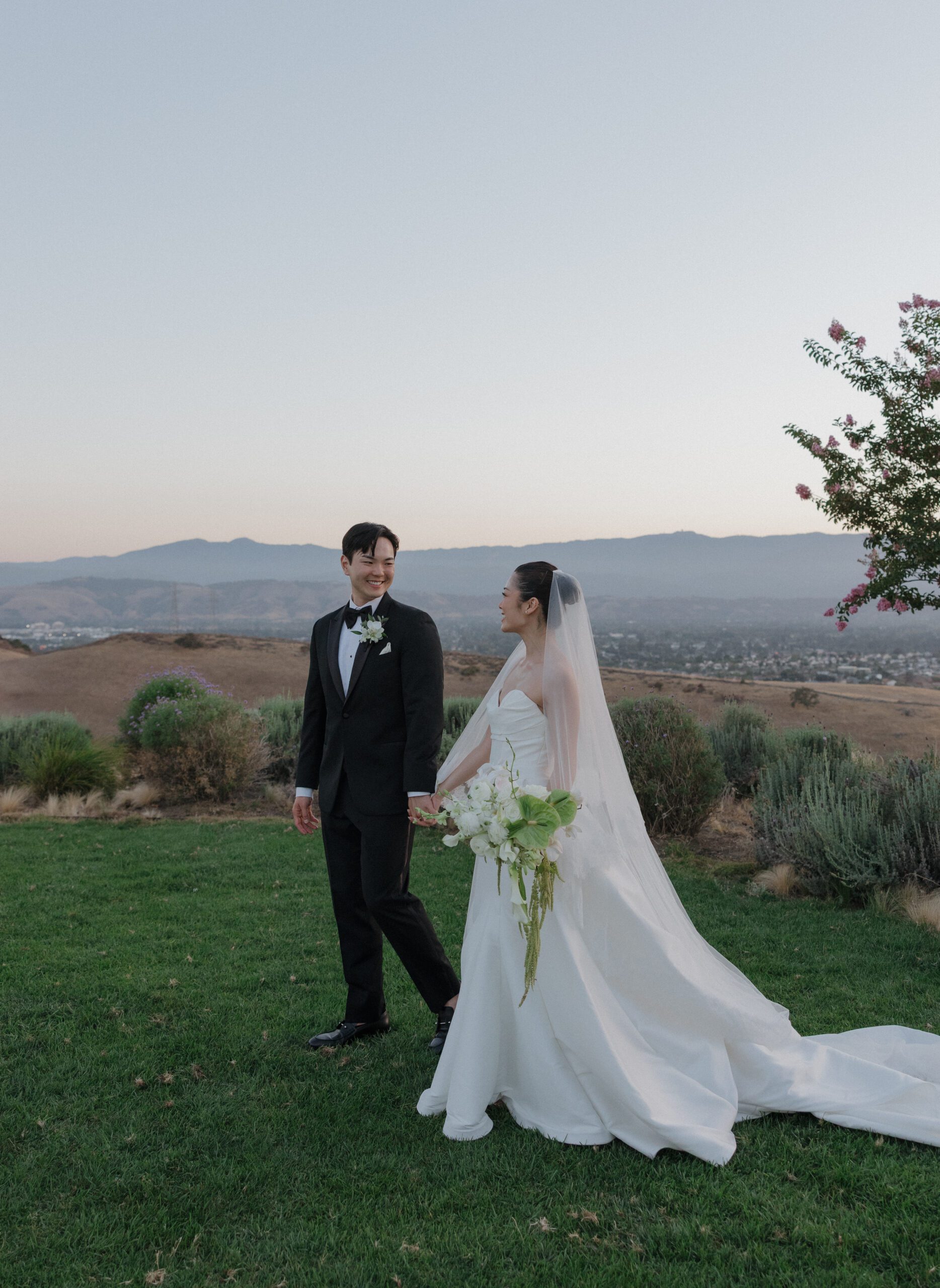 A bride and groom walking in front of mountain views at their Northern California wedding venue