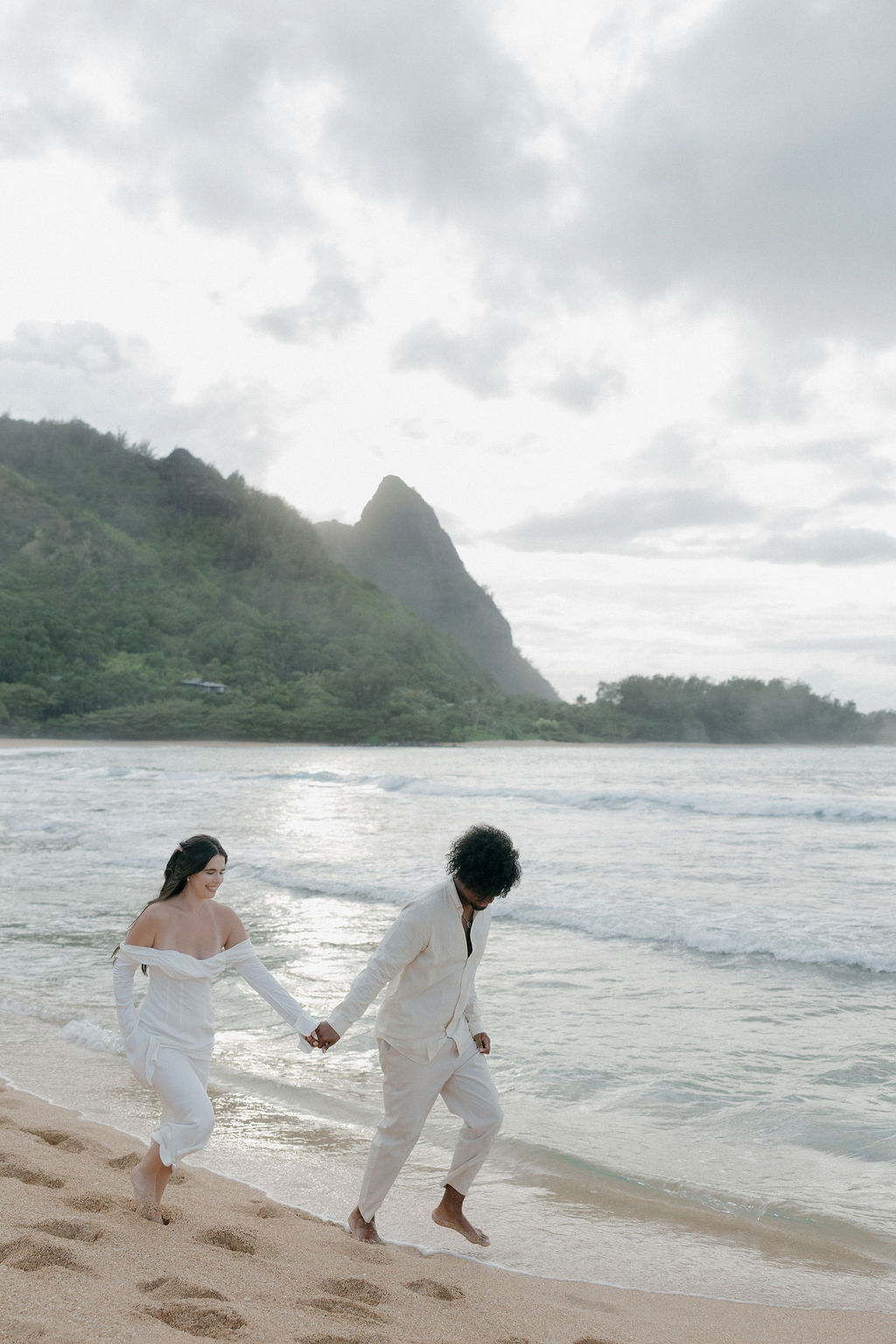 A couple running on a Kauai beach during elopement photos