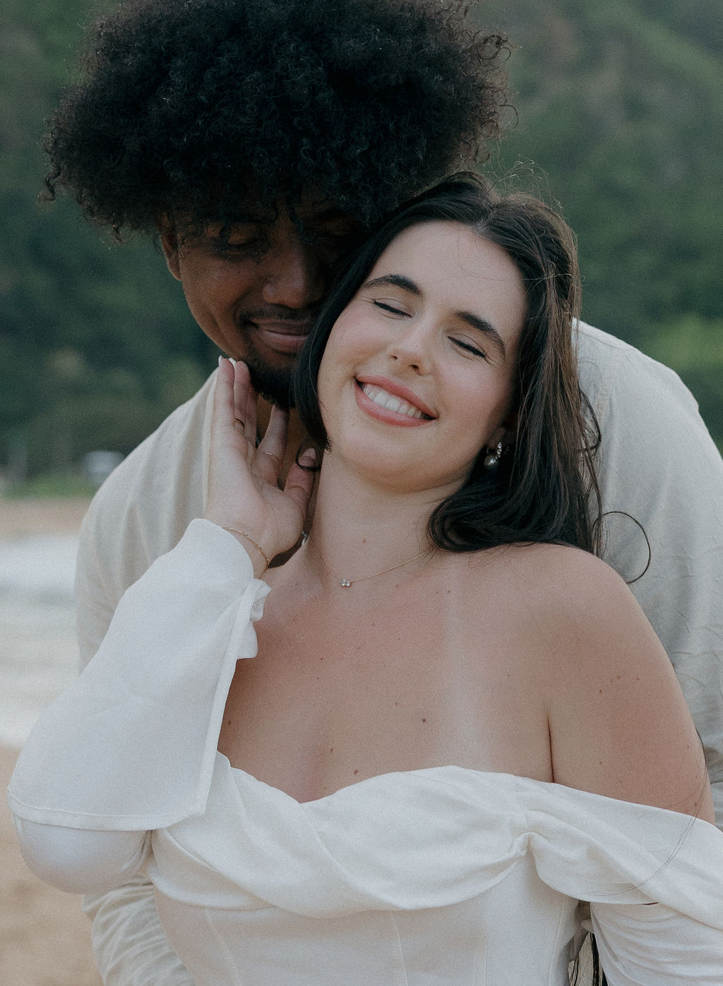 A couple posing for elopement photos on a Tunnels Beach