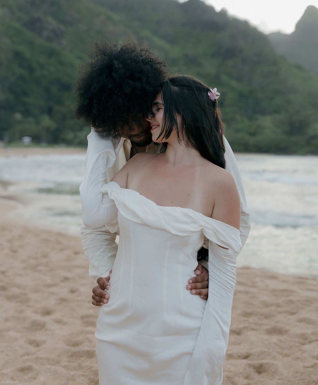 A couple posing for elopement photos on a Tunnels Beach