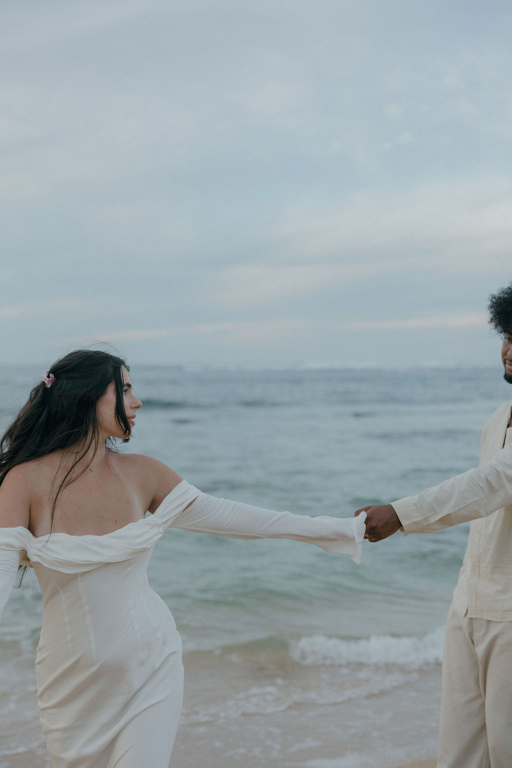 A couple reaching for each other on the beach