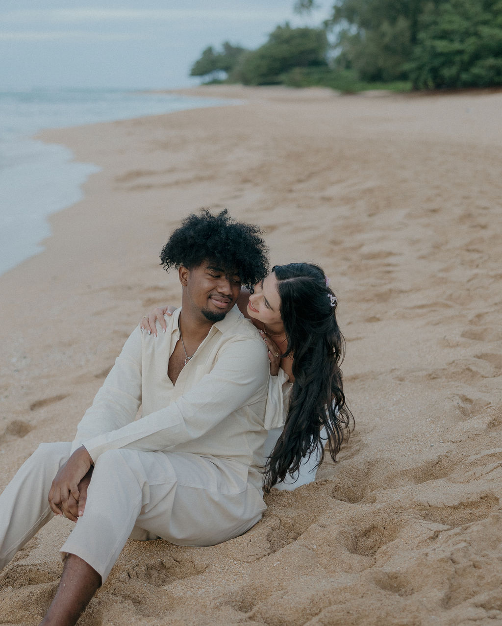 A bride and groom sitting on the beach for Kauai elopement photos