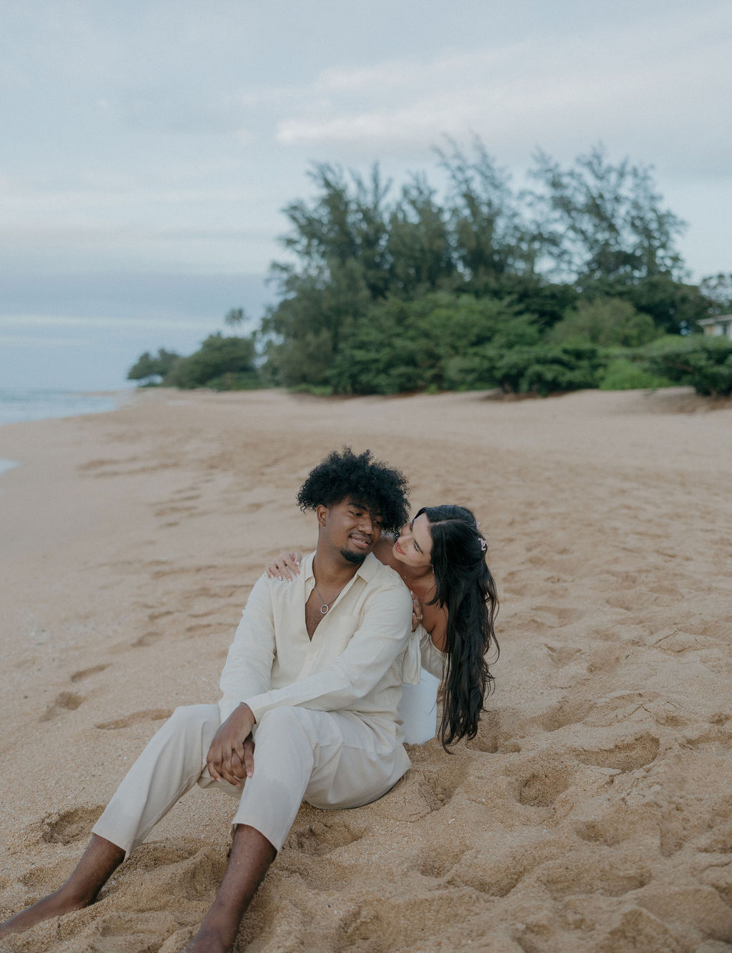 A bride and groom sitting on the beach for Kauai elopement photos
