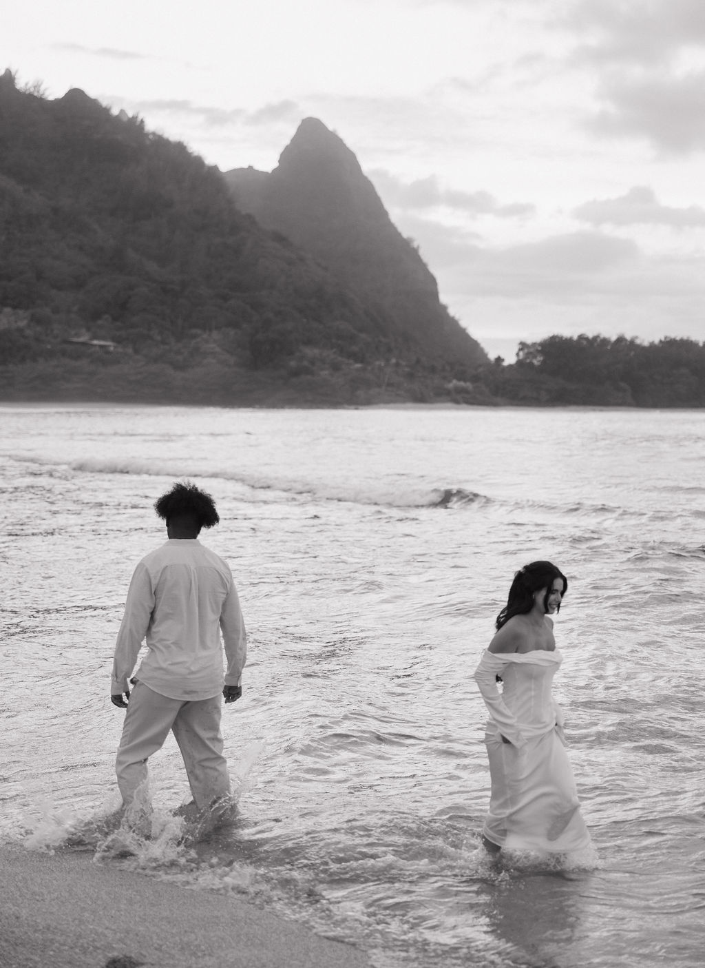 A bride and groom in the ocean on a Kauai beach 