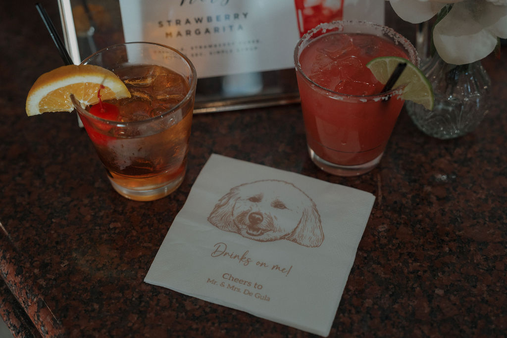 A bride and groom's custom wedding drinks with their dog printed on the bar napkins