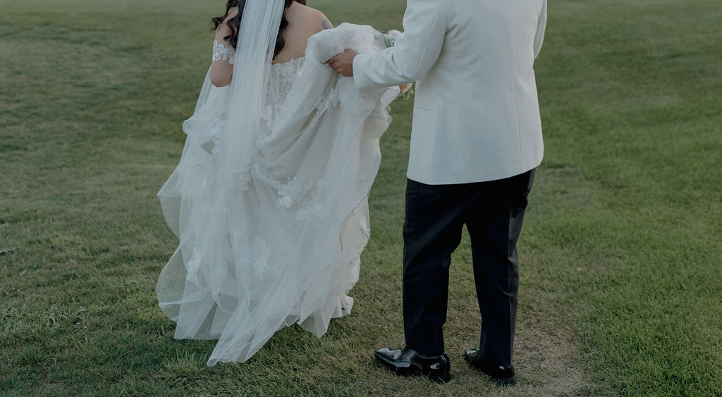 A groom carrying a bride's wedding dress train