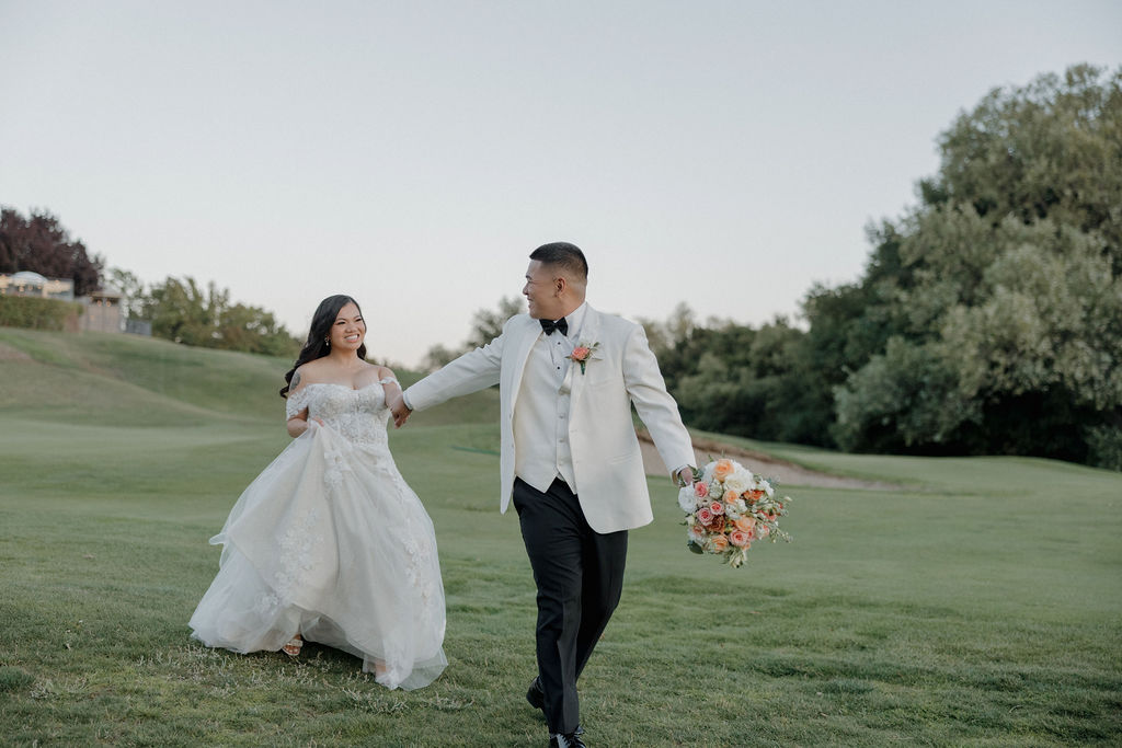 A bride and groom running across the lawn at the wedding venue they selected in their wedding vendor checklist