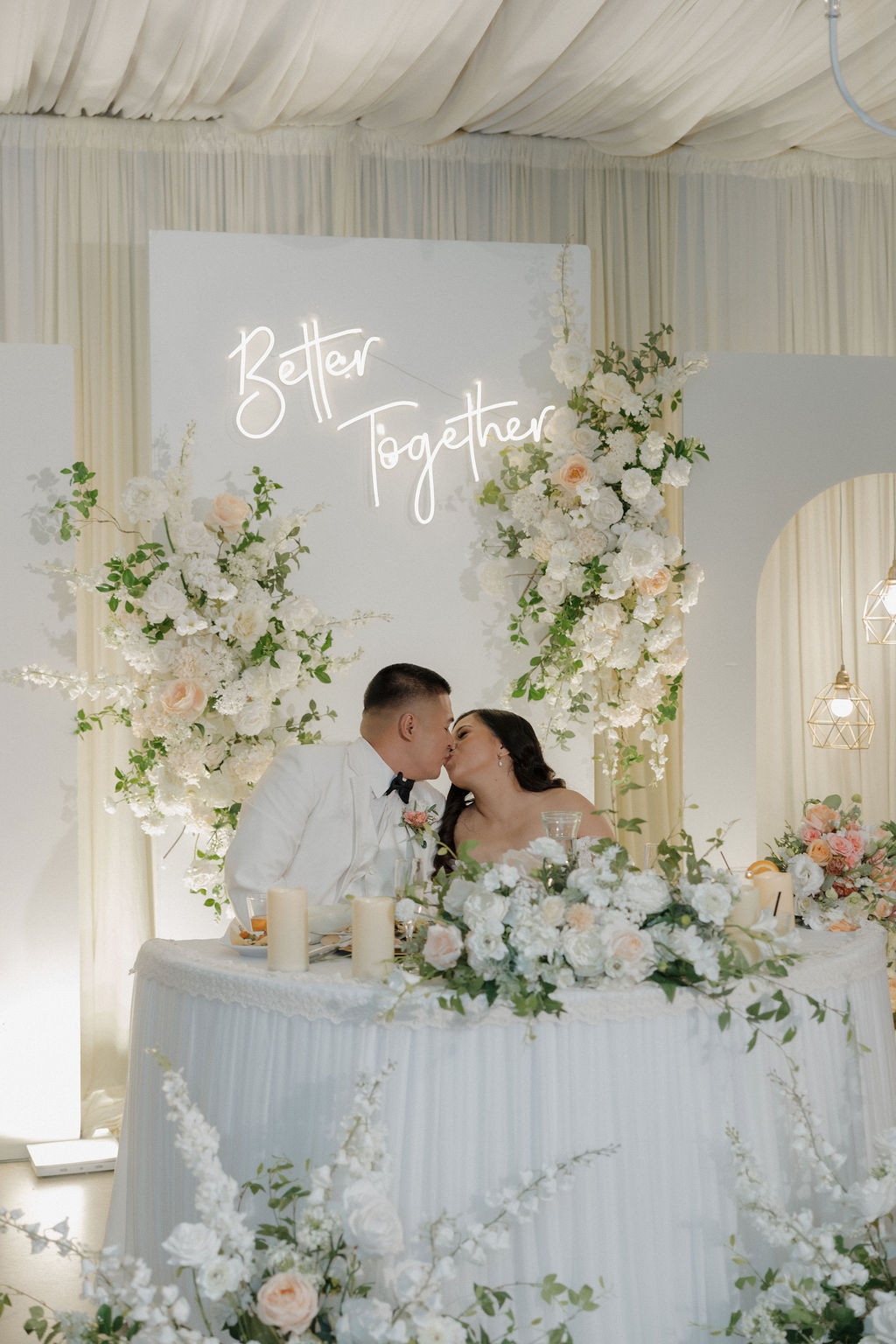 A bride and groom kissing at their wedding sweetheart table