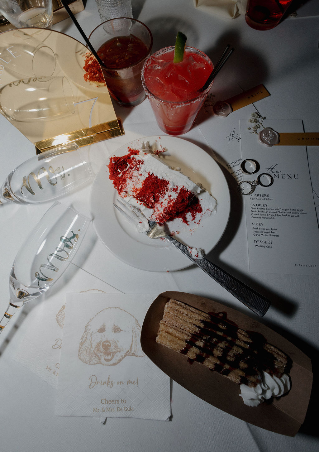 A wedding reception flat lay with wedding menus, cake, and cocktails