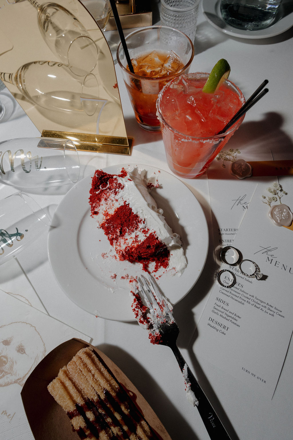 A wedding reception flat lay with wedding menus, cake, and cocktails
