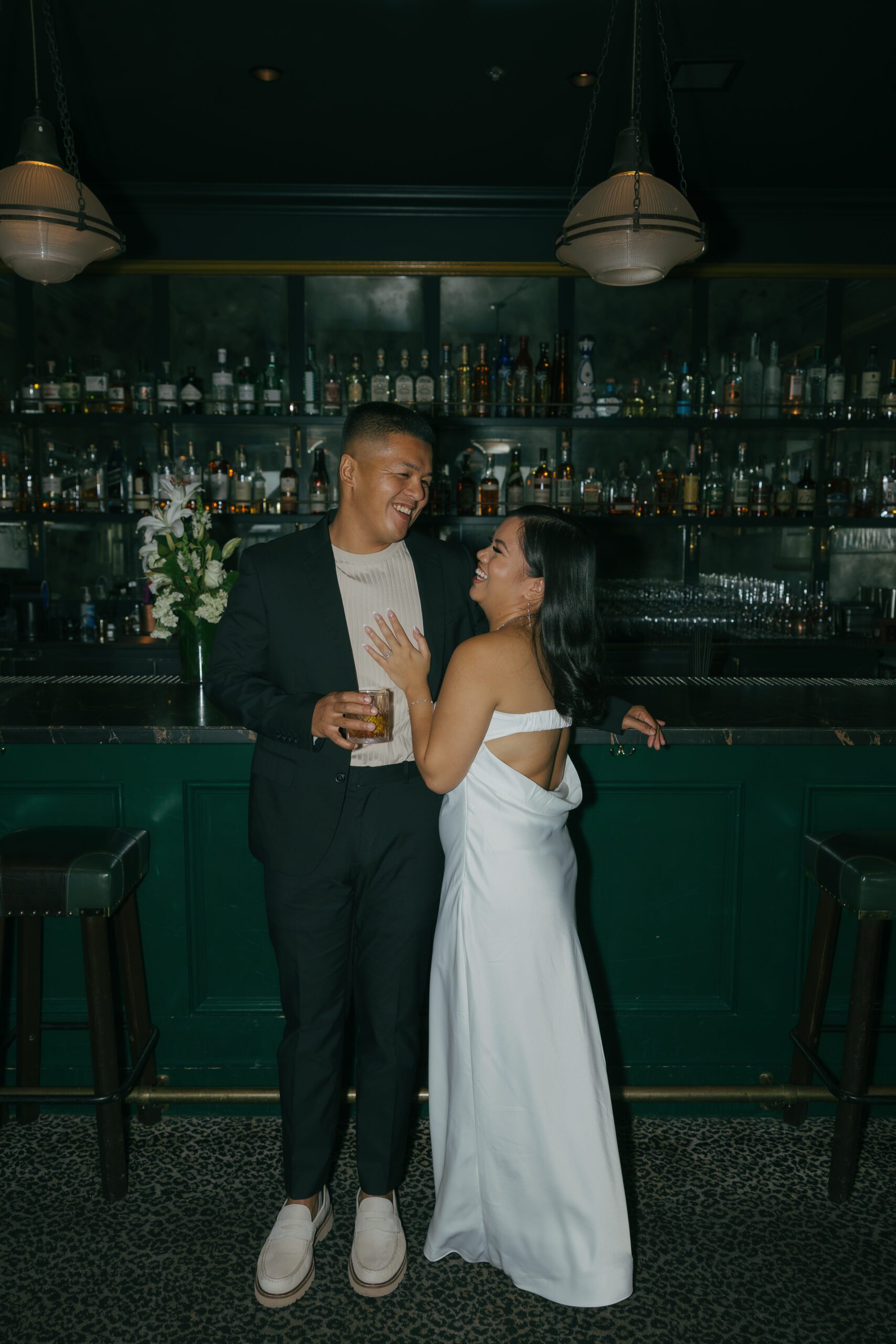 A couple posing in classy engagement photo shoot outfit ideas for a bar engagement photoshoot