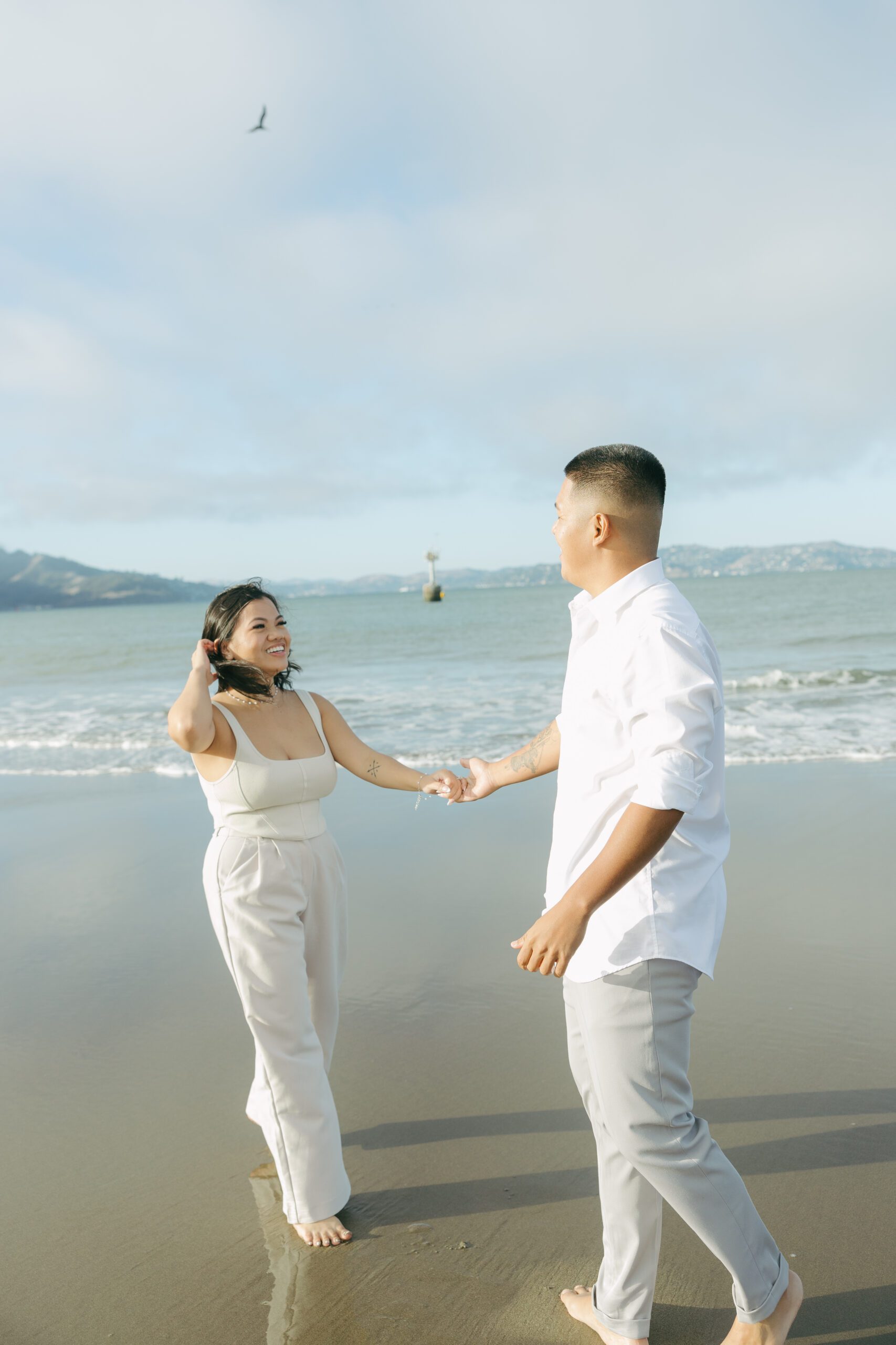 A couple taking beach engagement photos in casual outfits