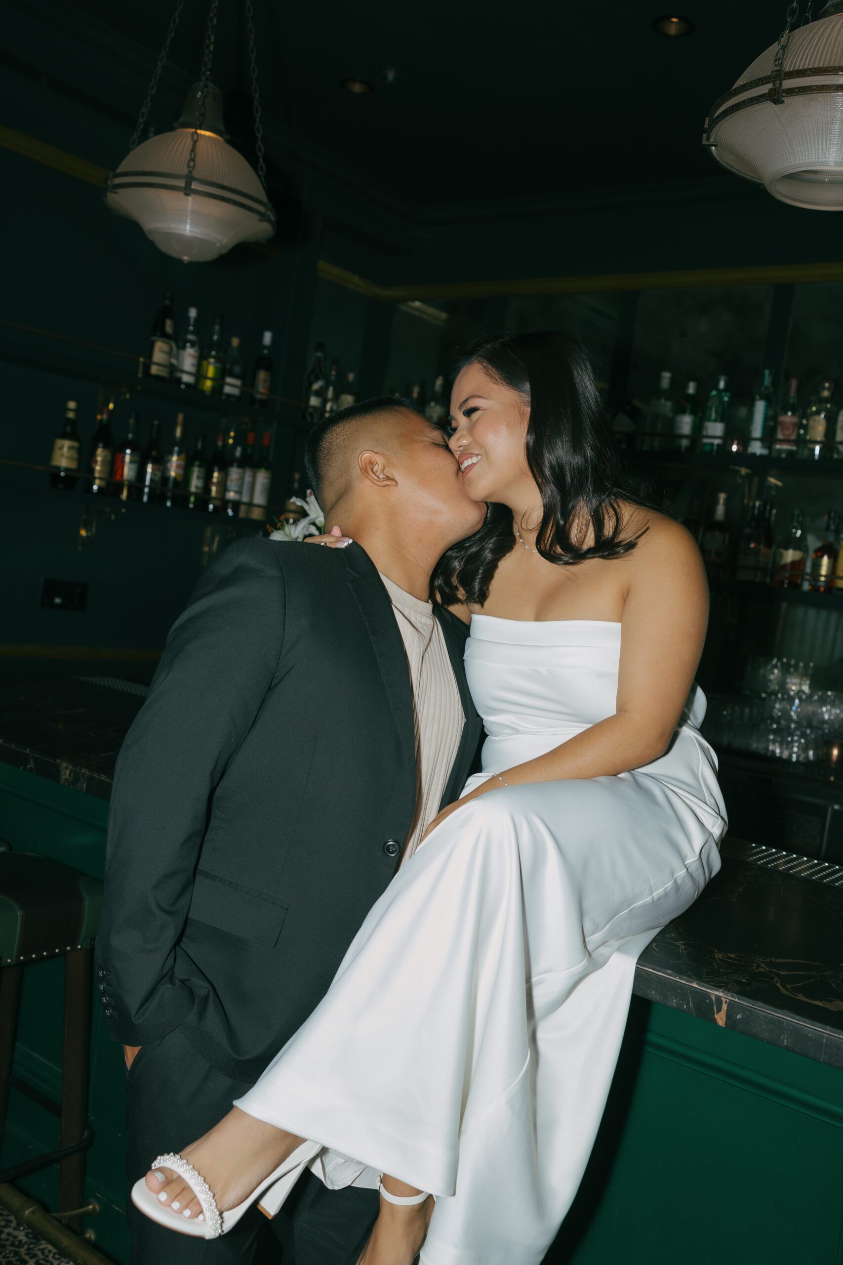 A couple posing in classy engagement photo shoot outfit ideas for a bar engagement photoshoot