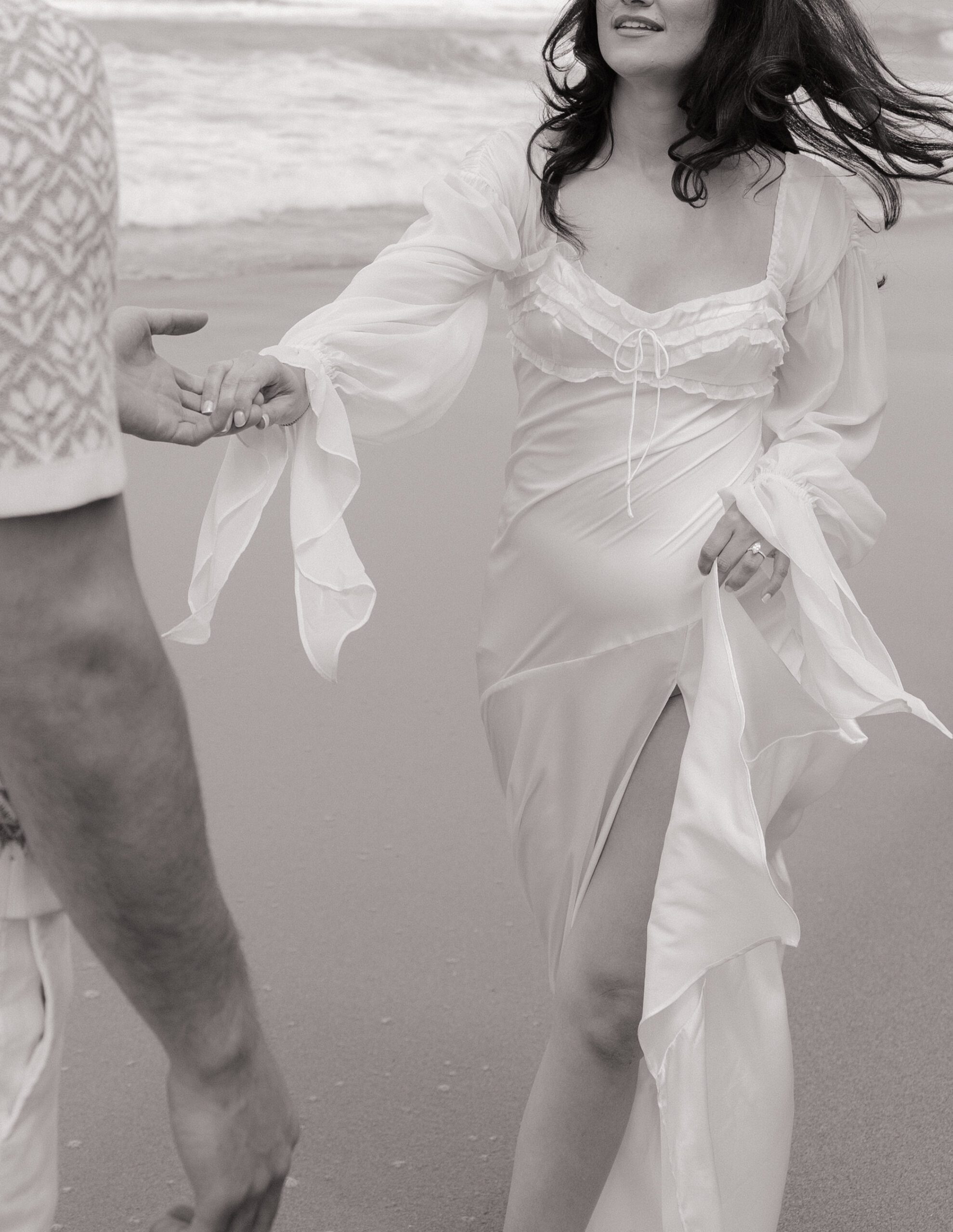 A black and white photo of a beach engagement photo shoot dress